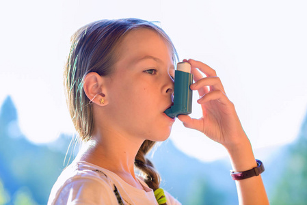 女孩在公园里使用哮喘吸入器