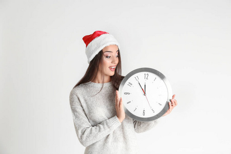 年轻女子在圣诞老人的帽子与时钟