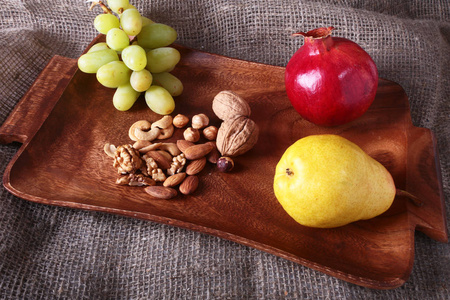 在木托盘上的新鲜有机水果。什锦的苹果 梨 葡萄 干果和坚果