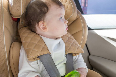 孩子坐在婴儿车座上。Isofix 夹紧。米色汽车座椅在明亮的沙龙