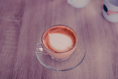 热咖啡用心弥补的玻璃杯子里的牛奶奶油的脸上