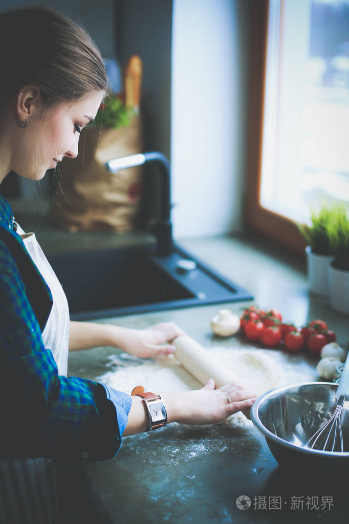 美丽的女人,烹饪厨房站在桌子上的蛋糕
