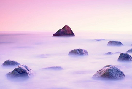 在岩石海岸的海上日落。低快门速度平稳水位和梦幻效果