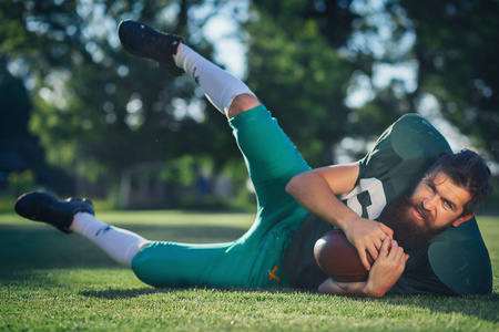 绿色体育的美式足球球员制服以黑色长长的胡须列车在足球场上