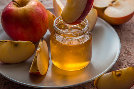有机蜂蜜在板上的玻璃罐子和红苹果