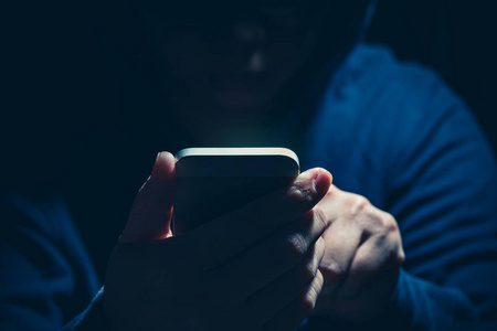 戴兜帽的黑客犯罪使用手机互联网黑客在照片