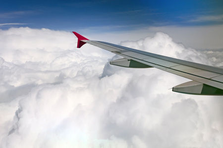 在厚云和蓝色背景下的喷气式飞机机翼视图