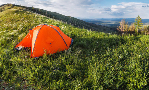 橙色的徒步旅行帐篷下新鲜的青草，夏天户外休闲概念在山顶