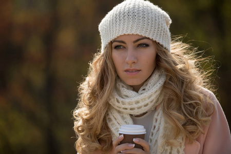 女人的围巾，帽子在公园，在秋季的一天，喝热茶模糊背景