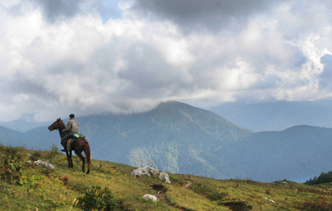 骑马的人留在峰山和其余来自自然的冒险。山和云的背景