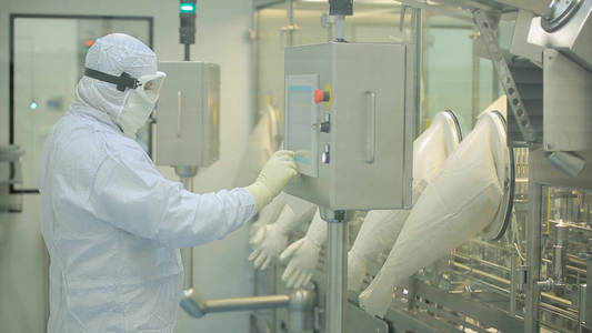 制药生产线工人在工作。机械臂在包装生产线的制药厂起重安瓿。制药行业。安瓿包装机