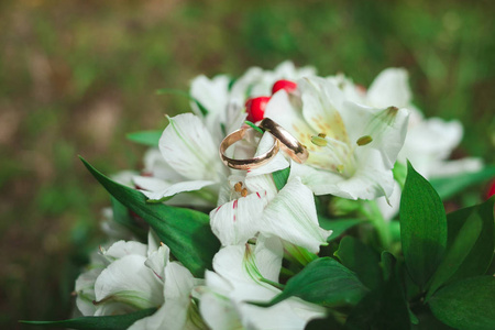 美丽的金色结婚戒指与婚礼花束新娘在绿草夏季特写