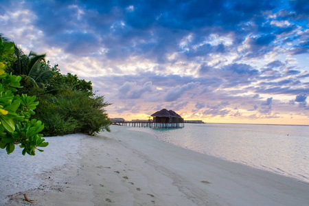 在马尔代夫岛沙质海滩与色彩斑斓的天空和浪的大海上空的云块戏剧性的美丽的日落景观