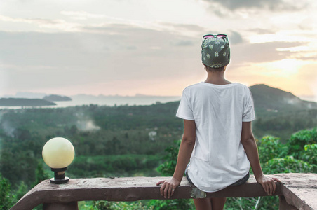 一个人背影一个女人坐在高和观看日落的背影照片