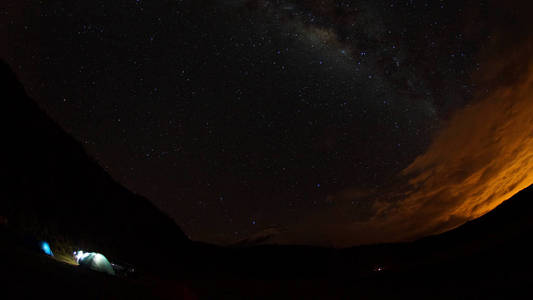 科托帕希在后台星光灿烂的夜晚点燃帐篷的视图。广角