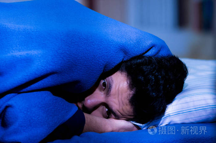 英俊的年轻男子躺在床上用眼睛打开痛苦失眠和睡眠障碍思考他的问题
