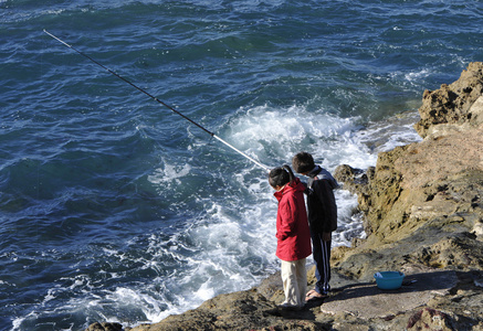 两个年轻的渔民在岩石上