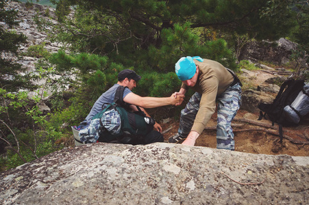 露营者帮助另一个攀爬岩石