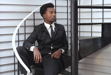 年轻男子黑色西装和领带坐在楼梯上的商人专业
