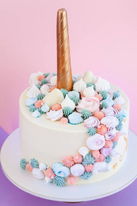 独角兽层状蛋糕装饰着蛋白甜饼。粉红色的背景