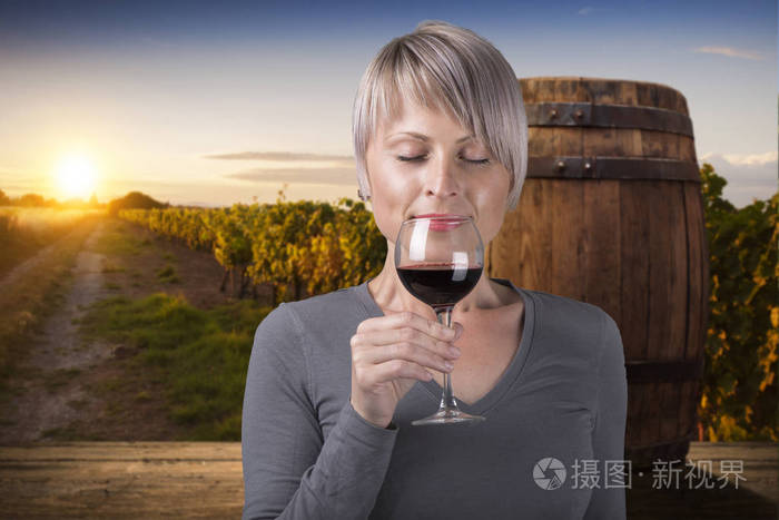 在喝葡萄酒的葡萄园的年轻黑发美女的画像