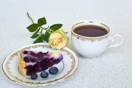 一块板上杯茶蓝莓馅饼和白色背景上的白玫瑰