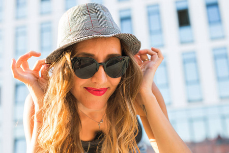 阳光的生活方式特写时尚的年轻时尚时髦的女人走在街上，穿着新潮的衣服和帽子的肖像