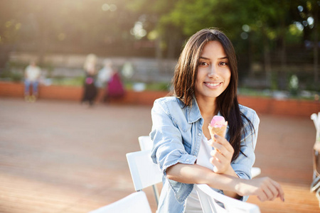 女孩微笑着看着相机享受品味阳光灿烂的夏天一天在公园里吃冰淇淋