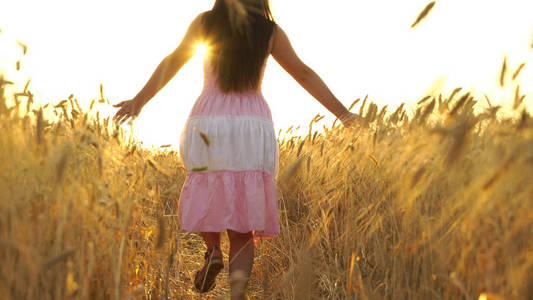 穿裙子的漂亮女孩奔跑着穿过田地