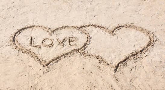 在沙滩上画的用词爱的心。海滩婚礼概念