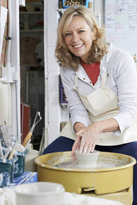 成熟的女人在陶工轮在工作室工作的肖像