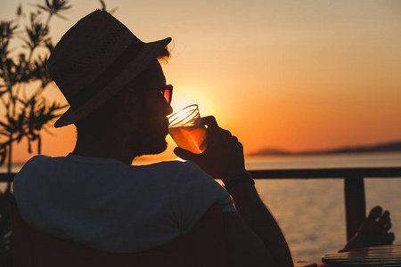 年轻人在海滩酒吧享受日落海滩上的人们在聚会上喝酒两个年轻人在海滩