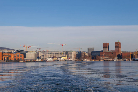港口有船，新建筑物和背景上的市政厅在日落时分在奥斯陆，挪威