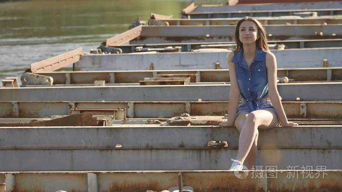 那个女孩正坐在桥上.性感漂亮的女孩的生活方式坐在室外的桥梁