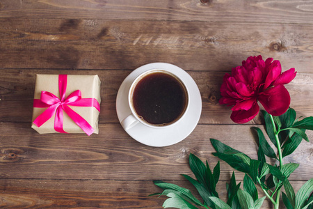 一杯咖啡 粉红牡丹图案及礼品盒木制背景上。早上好。妇女或母亲节的背景。顶视图