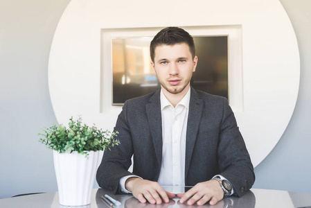 西装坐在办公室里,看着相机直接严重的年轻人照片