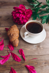 一杯咖啡 红牡丹图案和羊角面包上木制的背景。早上好。妇女或母亲节的背景