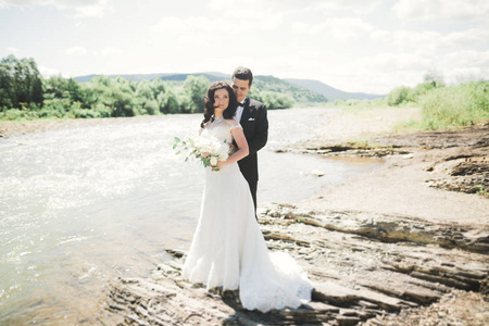 美丽婚礼情侣接吻和拥抱接近岸边的石头山区河流