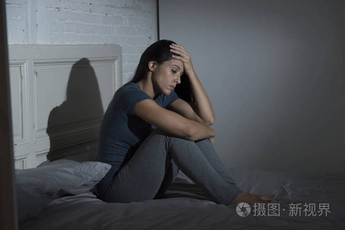 悲伤和沮丧拉丁美女坐在家里的床上失意痛苦抑郁
