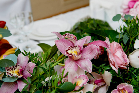 婚礼表装饰新婚夫妇。在鲜花的桌子上的歌曲。粉红色和白色的调色板 玫瑰 兰花