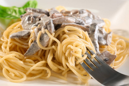 美味的意大利面和白汁蘑菇上叉