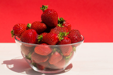 草莓在玻璃碗里，红色背景