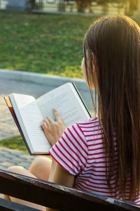 阅读一本书和放松在公园里一名年轻女子的背影