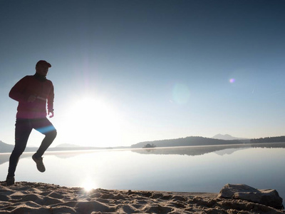 男孩很快跑在早晨的海滩上.运动员跑步,跑步的家伙照片