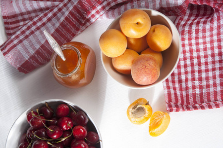 在碗中，用红色和白色的毛巾，手工夏天空白的白色桌子上一罐果酱杏子