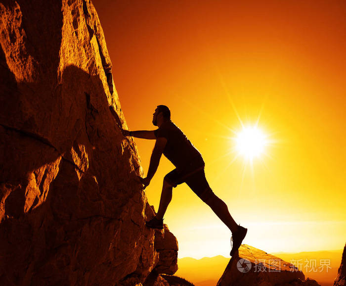 一个人爬上山顶反对日出的剪影