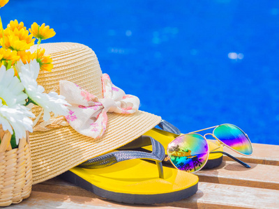 与夏天帽子 拖鞋 洗发水 防晒乳液和花在泳池边的太阳镜。假期和松弛，夏天旅游概念
