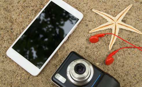 旅游规划和假期在海砂的概念。顶视图智能手机 相机 海星 耳机