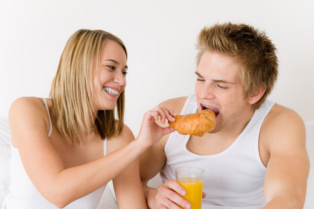 早餐年轻夫妇一起吃牛角面包