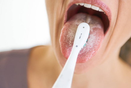 清洁舌头用牙刷的年轻女子的特写